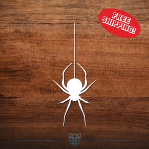 May include: A white spider silhouette suspended by a single line against a dark wood grain background. A red oval with the text "FREE SHIPPING!" is in the upper right corner. The spider has a round body and eight legs.