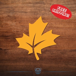 May include: A golden yellow maple leaf illustration on a dark wood grain background. A red oval with the words "FREE SHIPPING!" is in the upper right corner. The leaf is a symbol of autumn and fall.