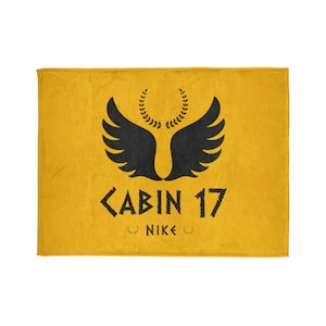 May include: A yellow fleece blanket with a black winged symbol and the text "CABIN 17" and "NIKE" in black.