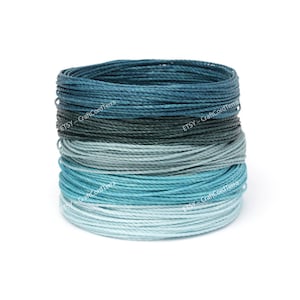 May include: A spool of blue, teal and green waxed cotton cord. The cord is wound in a gradient pattern, starting with the darkest blue at the bottom and fading to the lightest green at the top.