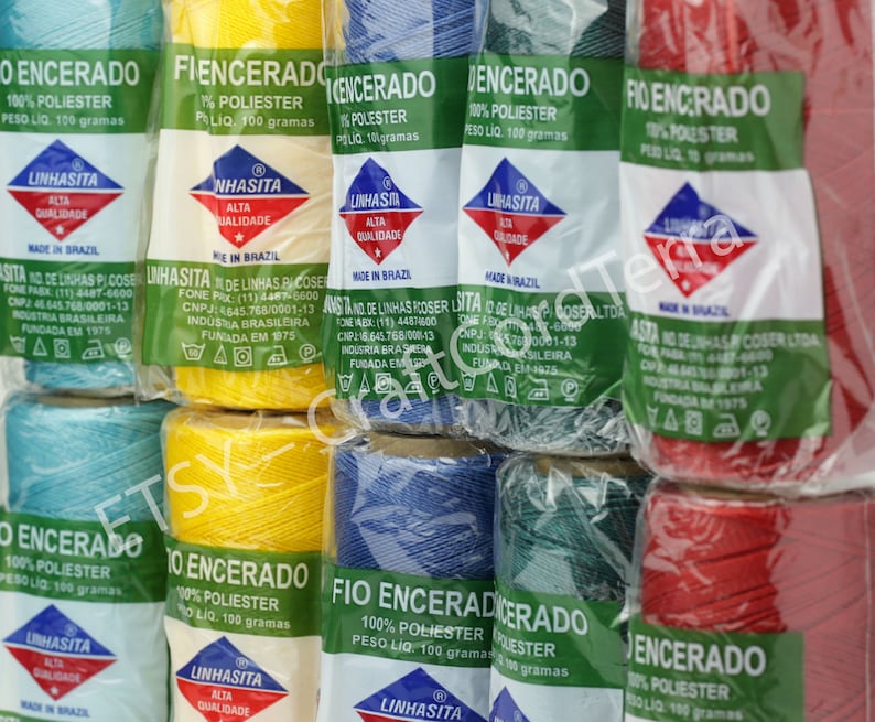 May include: Assortment of spools of waxed thread in various colors, including blue, yellow, red, and green. Each spool is labeled "Fio Encerado" and "100% Polyester" with the weight listed as 100 grams. The label also includes the brand name "Linhasita" and the text "Alta Qualidade" (High Quality) and "Made in Brazil".