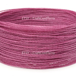 May include: A close-up of a spool of pink waxed cotton cord. The cord is wound tightly and is ready to be used for crafting projects.