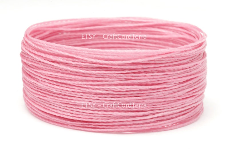 May include: A spool of pink waxed cotton cord. The cord is wound tightly and is ready to be used for crafting projects.