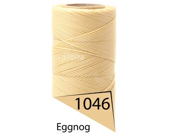 May include: A spool of Eggnog-colored cord. The cord is tightly wound around a cardboard core. A tan-colored label with the number "1046" and the word "Eggnog" is attached to the spool.