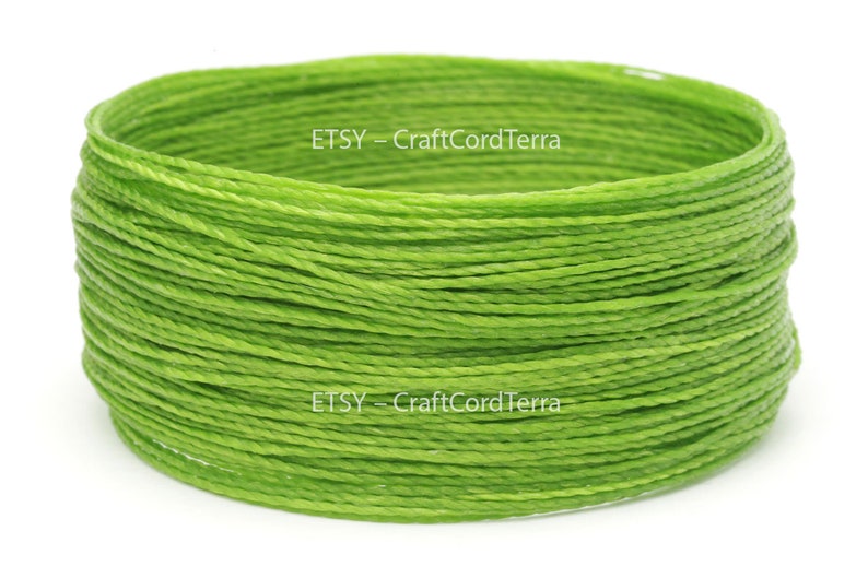 May include: A close-up of a spool of bright green waxed cotton cord. The cord is tightly wound and the spool is labeled "ETSY - CraftCordTerra".