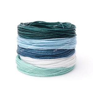 May include: A stack of spools of colorful waxed cotton cord in shades of teal, blue, white, and mint green. The cord is perfect for crafting projects like macrame, jewelry making, and more.