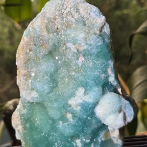 Puede incluir: Primer plano de un esp&eacute;cimen mineral de color turquesa. La piedra tiene una superficie rugosa y texturizada con &aacute;reas de azul claro y blanco. El mineral parece ser un grupo de peque&ntilde;os cristales.