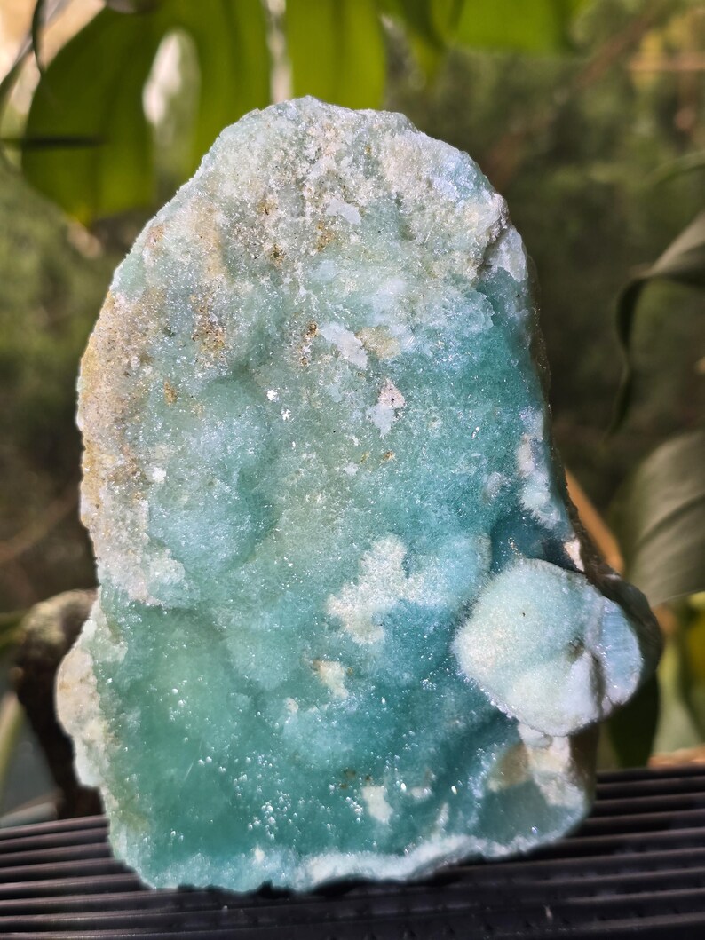 Puede incluir: Primer plano de un esp&eacute;cimen mineral de color turquesa. La piedra tiene una superficie rugosa y texturizada con &aacute;reas de azul claro y blanco. El mineral parece ser un grupo de peque&ntilde;os cristales.