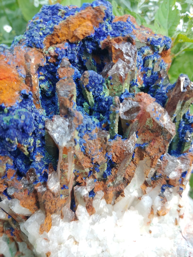May include: A cluster of quartz crystals with a blue and green mineral, possibly azurite and malachite, embedded in the center. The crystals are clear and have a rough, natural texture.