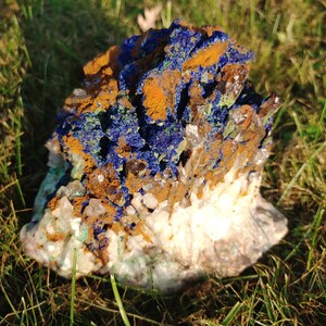 May include: A cluster of blue azurite, green malachite, and clear quartz crystals on a bed of white calcite. The crystals are arranged in a natural, organic pattern, creating a beautiful and unique display.