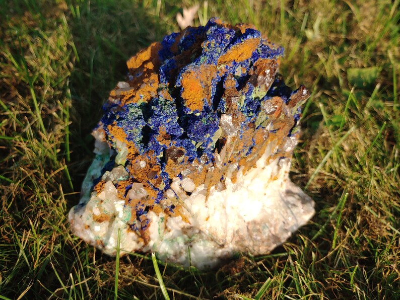May include: A cluster of blue azurite, green malachite, and clear quartz crystals on a bed of white calcite. The crystals are arranged in a natural, organic pattern, creating a beautiful and unique display.