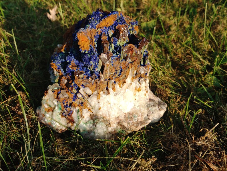 May include: A cluster of blue azurite crystals with brown and white quartz crystals. The crystals are arranged in a natural formation and have a rough, textured surface.