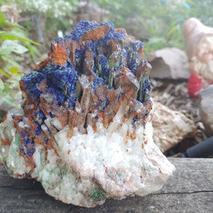 May include: A cluster of crystals with a mix of blue, green, white, and brown colors. The crystals are arranged in a natural formation, with some pointing upwards and others pointing downwards.