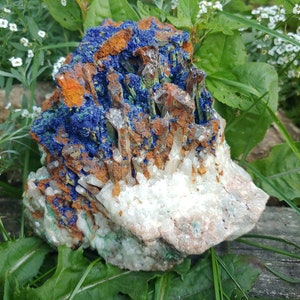 May include: A cluster of crystals with a mix of blue, green, white, and brown colors. The crystals are arranged in a natural formation and have a rough, textured surface.