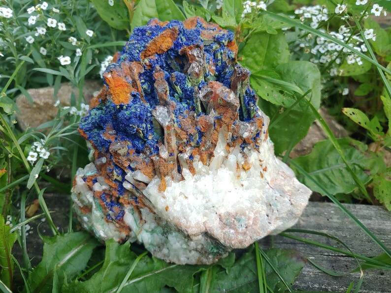 May include: A cluster of crystals with a mix of blue, green, white, and brown colors. The crystals are arranged in a natural formation and have a rough, textured surface.