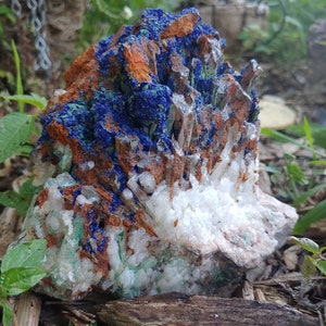 May include: A cluster of white quartz crystals with blue azurite and green malachite inclusions. The crystals are arranged in a natural formation, with some of the quartz crystals pointing upwards.