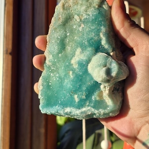 Puede incluir: Un esp&eacute;cimen mineral grande, de forma irregular, con un vibrante tono turquesa. La piedra tiene una superficie rugosa y texturizada con &aacute;reas de coloraci&oacute;n m&aacute;s clara, casi blanca. Una formaci&oacute;n m&aacute;s peque&ntilde;a, en forma de hongo, est&aacute; adherida al cuerpo principal del mineral.