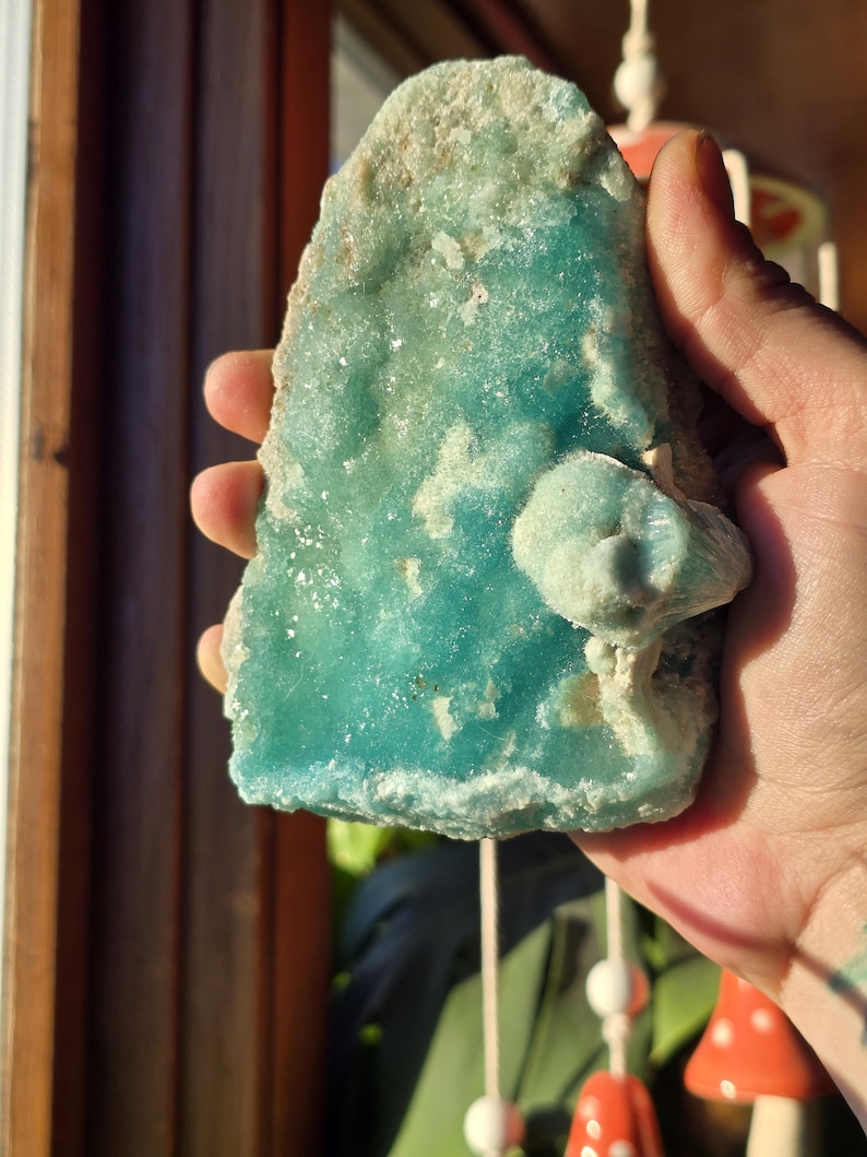 Puede incluir: Un esp&eacute;cimen mineral grande, de forma irregular, con un vibrante tono turquesa. La piedra tiene una superficie rugosa y texturizada con &aacute;reas de coloraci&oacute;n m&aacute;s clara, casi blanca. Una formaci&oacute;n m&aacute;s peque&ntilde;a, en forma de hongo, est&aacute; adherida al cuerpo principal del mineral.