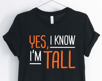 Puede incluir: Camiseta negra con texto blanco que dice "YES, I KNOW I'M TALL" con la palabra "TALL" en naranja.