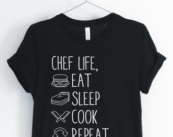 May include: Black t-shirt with white text that reads "Chef Life, Eat, Sleep, Cook, Repeat". The text is accompanied by icons of a hamburger, a bed, crossed knives, and a recycling symbol.