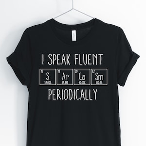 May include: Black t-shirt with white text that reads "I speak fluent S Ar Ca Sm periodically". The text is arranged in a periodic table format with the chemical symbols and atomic weights for sulfur, argon, calcium, and samarium.