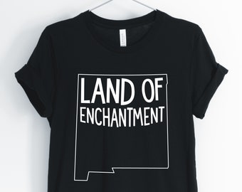 May include: Black t-shirt with a white outline of the state of New Mexico and the text "LAND OF ENCHANTMENT" in white.