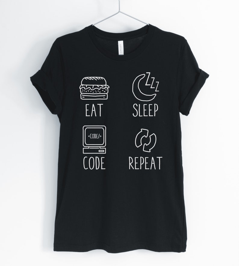 May include: Black t-shirt with a white graphic design that says "Eat, Sleep, Code, Repeat". The graphic includes icons for a hamburger, a crescent moon with zzz's, a computer screen with code, and a circular arrow.