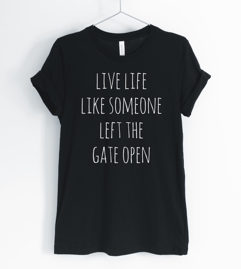May include: Black t-shirt with white text that reads "Live life like someone left the gate open."