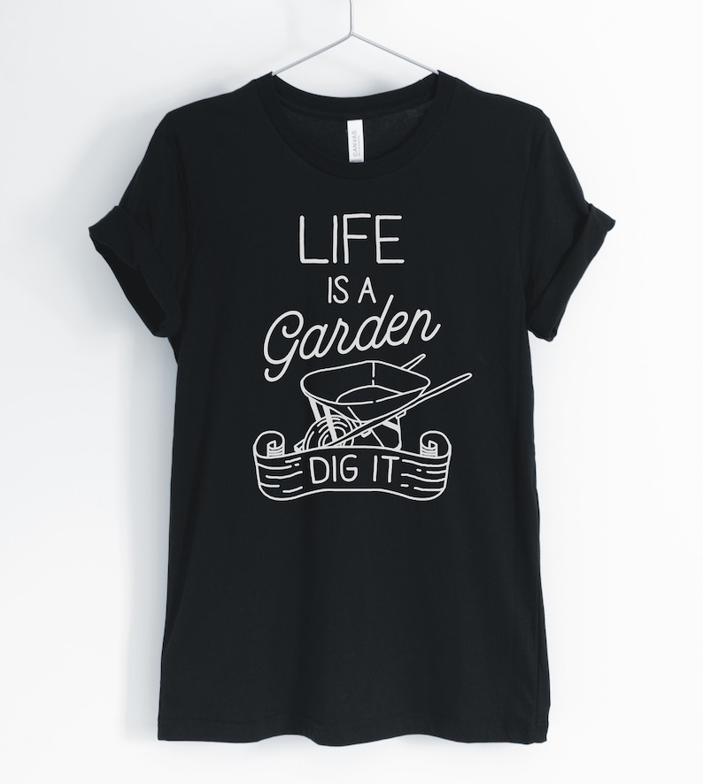 May include: Black t-shirt with a white graphic design that says "Life is a Garden, Dig It". The graphic includes a wheelbarrow and gardening tools.
