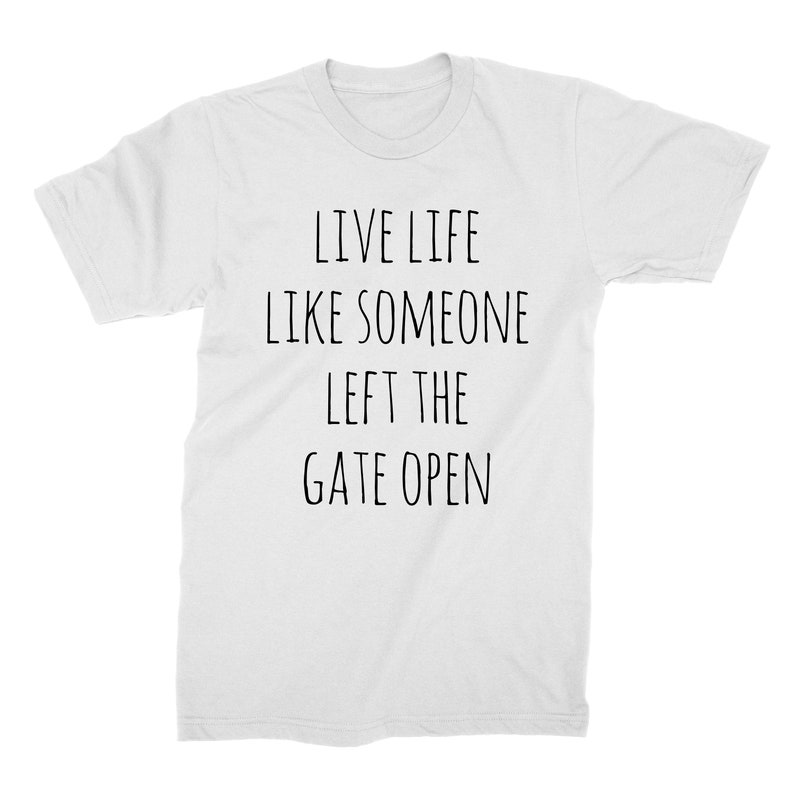 May include: White t-shirt with black text that reads "Live life like someone left the gate open."