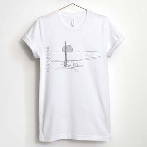 May include: White t-shirt with a line drawing of a tall building and a sun in the background. The text "東京スカイツリー" is printed on the left side of the shirt.