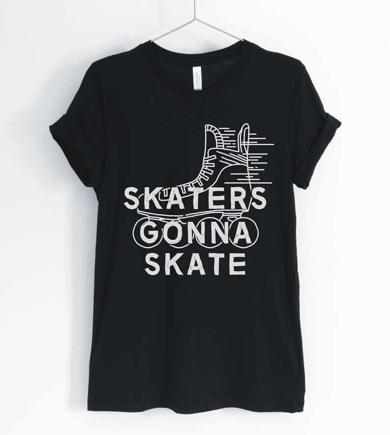 May include: Black t-shirt with white graphic of a roller skate and the text "SKATERS GONNA SKATE". The shirt is hanging on a metal hanger against a white background. The sleeves are rolled up.