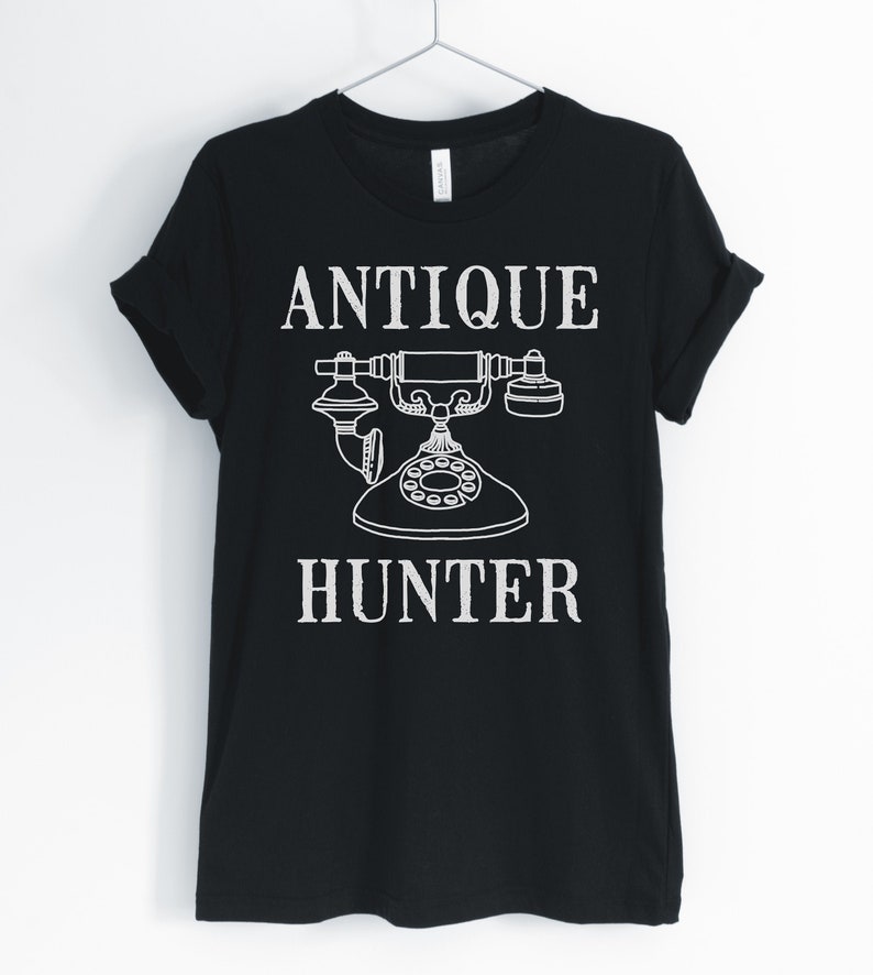 May include: Black t-shirt with white text that reads "Antique Hunter" and a vintage rotary phone graphic.