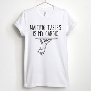 May include: White t-shirt with black text that reads "Waiting tables is my cardio" and a black line drawing of a hand holding a tray.