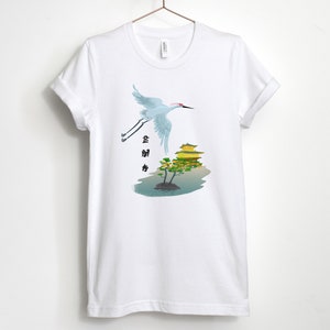 May include: White t-shirt with a graphic of a crane flying over a golden pagoda with a tree in front of it. The text "金閣寺" is written in black on the left side of the image.