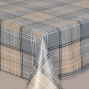 May include: A gray, tan, and white plaid tablecloth. The tablecloth has a classic plaid pattern with intersecting lines in various shades of gray, tan, and white. The fabric appears to be smooth and wrinkle-resistant, suitable for dining or decorative use.