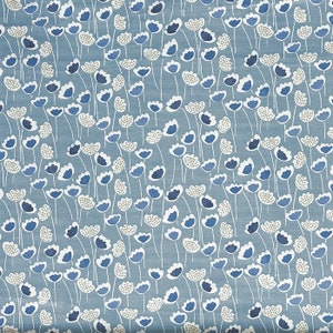 May include: A blue fabric featuring a floral design. The pattern consists of white, light blue, and dark blue flowers with thin white stems. The background is a solid, light blue colour.