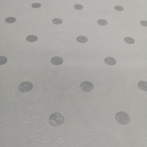 May include: White fabric with a repeating pattern of embossed gray circles. The fabric has a subtle textured pattern.