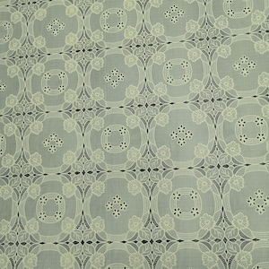May include: White lace fabric with a repeating pattern of circles and flowers. The fabric has a delicate, airy feel.