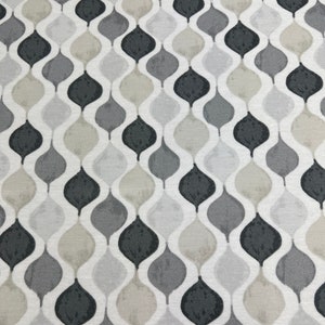 May include: A white fabric with a repeating pattern of grey, black, and beige teardrop shapes.
