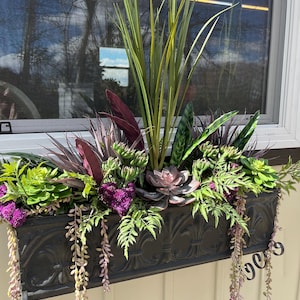 Peut inclure: Une jardinière en métal noir remplie de plantes vertes et violettes, dont des succulentes, des fougères et des vignes retombantes.