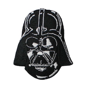May include: Black and white embroidered patch featuring the iconic helmet of Darth Vader. The patch has a detailed design with white stitching outlining the helmet's features against a black background. The patch is likely for clothing or accessories.
