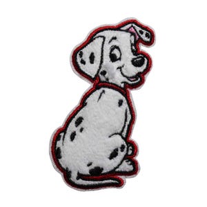 May include: Embroidered patch featuring a cartoon Dalmatian dog in a sitting position. The dog is white with black spots and a red outline. The patch is designed for application on clothing or accessories.