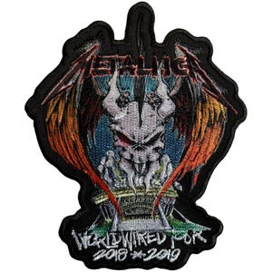 May include: Embroidered patch featuring a skull with red eyes, wings, and the band name "METALLICA" in red. The patch also includes the text "WORLDWIRED TOUR 2018 * 2019" in white, set against a black background.