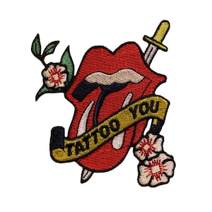 May include: Embroidered patch featuring a red mouth with a tongue, a dagger, and a banner that reads "TATTOO YOU" in black letters. The patch also includes floral accents in white, red, and green. The patch is designed to be ironed on or sewn onto clothing or accessories.