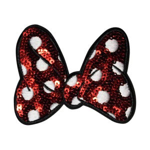 May include: A red sequined bow with white polka dots and a black border. The bow is a classic shape, perfect for adding a touch of sparkle to clothing or accessories. This item is ideal for crafting and DIY projects.