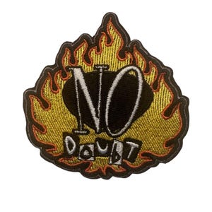 May include: Embroidered patch with a black oval design and the words "NO DOUBT" in white. The patch is surrounded by a yellow and orange flame design, with a black border. The patch is likely for clothing or accessories.