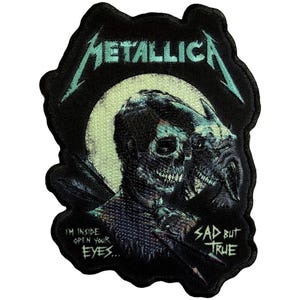 May include: Black embroidered patch featuring the band name "Metallica" in teal lettering. The patch depicts a skull-like figure with the text "I'M INSIDE OPEN YOUR EYES..." and "SAD BUT TRUE".