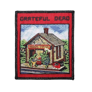 May include: Embroidered patch with a red border and background. The patch features the text "Grateful Dead" at the top. Below is a detailed illustration of a wooden building with two turtles and the text "Terrapin Station".