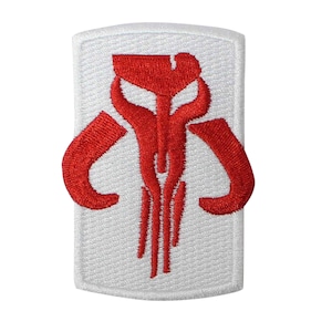 May include: Embroidered patch featuring a red Mandalorian skull design on a white rectangular background. The patch has a textured appearance, with the red design standing out against the white fabric. Ideal for jackets, bags, or cosplay.